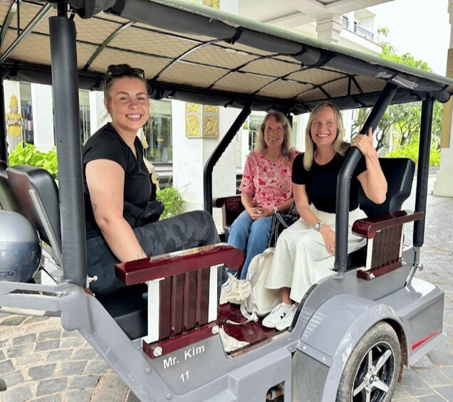 Three people in a golf cart labeled 'Mr. Kim 11' on a paved surface. 1