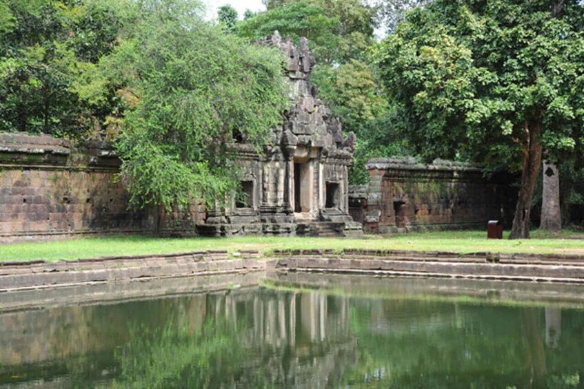 A temple complex with a central structure surrounded by a reflective pond, set within a lush green environment. 5