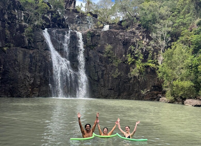 Una cascada, penya-segats rocosos i persones en una balsa verda en un riu. 2
