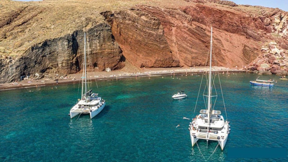 Una zona costiera con acque turchesi cristalline, scogliere rocciose e diverse barche a vela ancorate vicino alla riva. 3