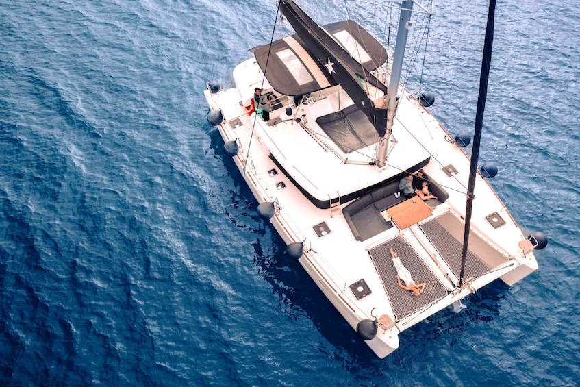 Uno yacht bianco con una stella a prua, una persona sul ponte e una persona in costume da bagno a poppa. 1