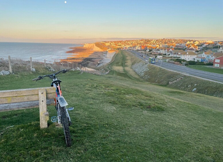 Ein Küstenort mit einem Fahrrad, das auf einem grasbewachsenen Hügel mit Blick auf das Meer abgestellt ist. 5