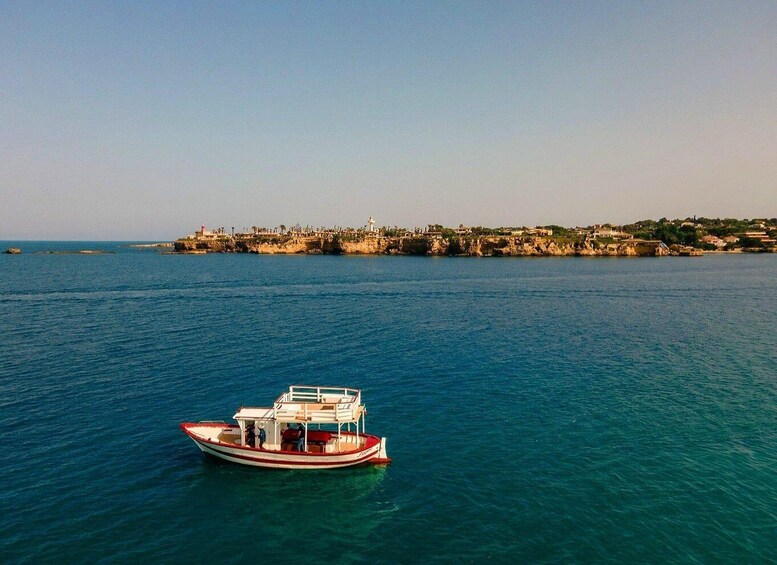 Un barco sobre aguas marinas tranquilas, con un pueblo costero al fondo. 2