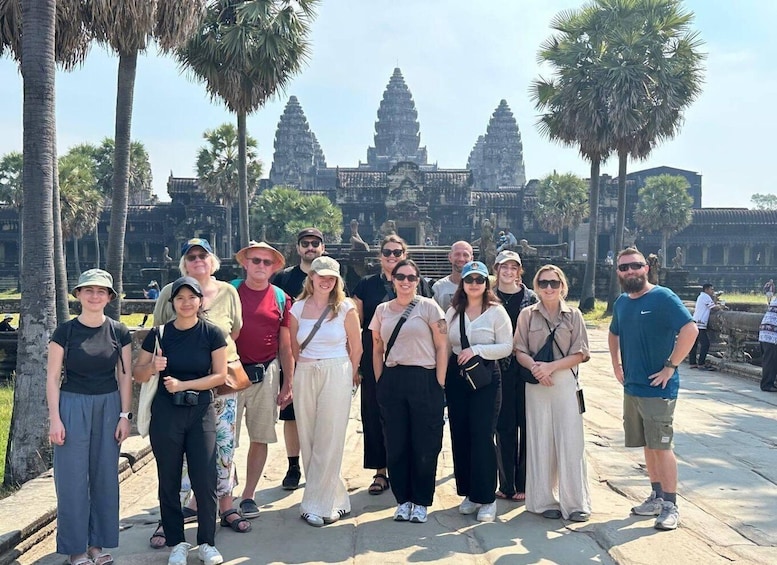 A group of people standing in front of Angkor Wat temple. 1