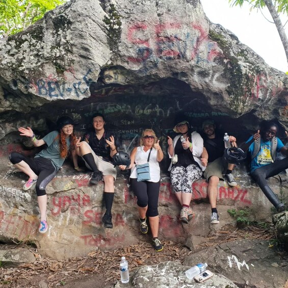 A group of people sitting on a rock with graffiti. 2