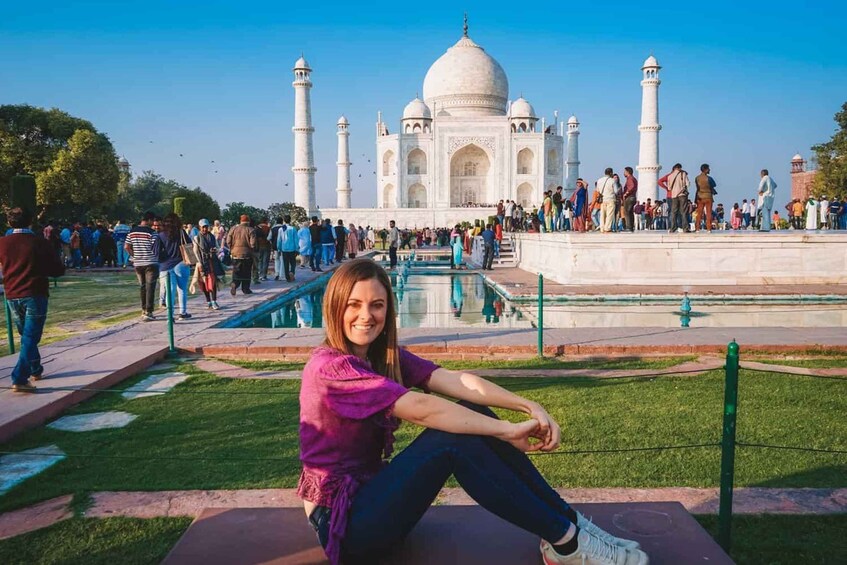 Une personne assise devant le Taj Mahal, avec une foule en arrière-plan. 2