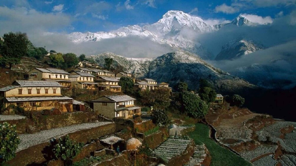 A village with traditional houses nestled in a mountainous area, with snow-capped peaks in the background. 5