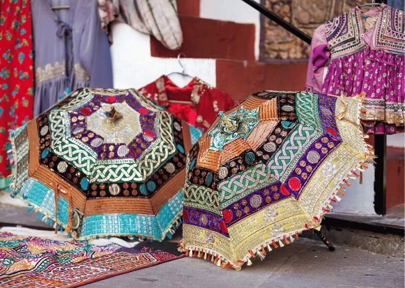 Intricately patterned carpets and textiles displayed on a street. 3