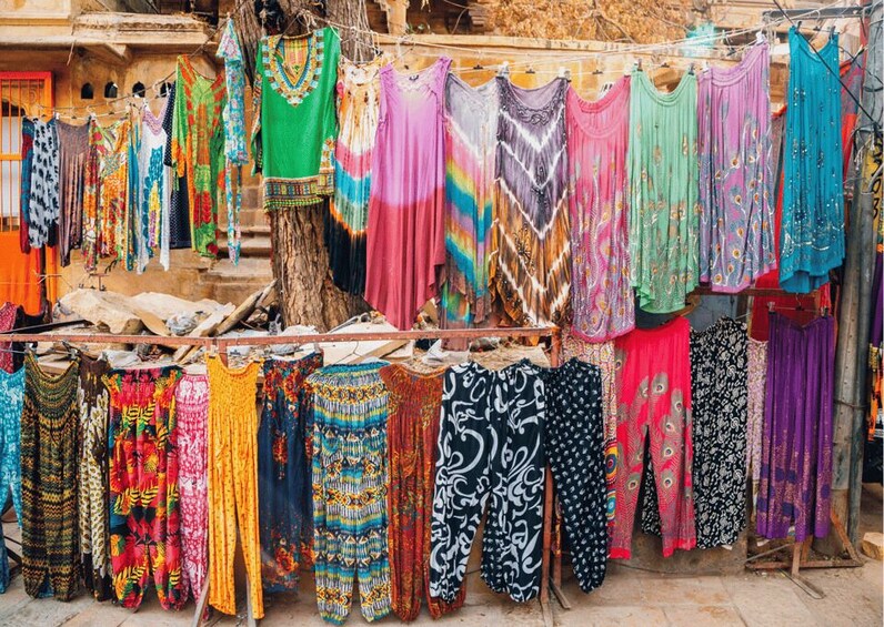 A variety of colorful garments hanging on racks outdoors. 5