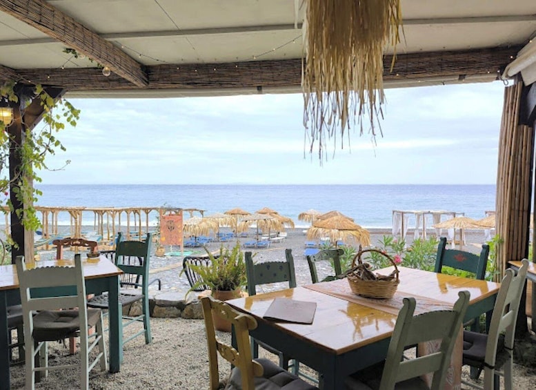 An outdoor dining area with tables and chairs overlooking a beach. 2