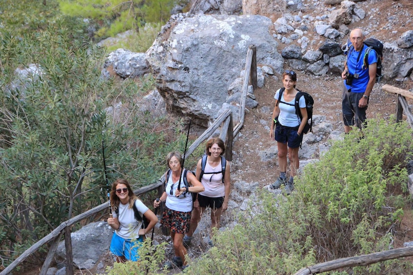A group of hikers on a rocky trail surrounded by greenery. 1