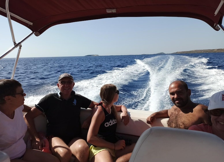 A group of people on a boat with a clear view of the ocean and distant land. 4
