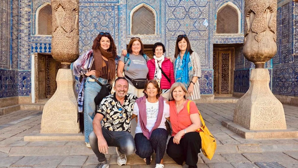 Un groupe de personnes posant devant un bâtiment orné de motifs complexes en carreaux bleus et blancs et de grandes colonnes décoratives. 3