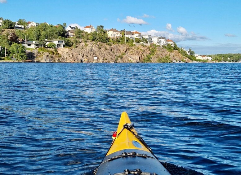 A yellow kayak on a body of water with houses on a hillside in the background. 5