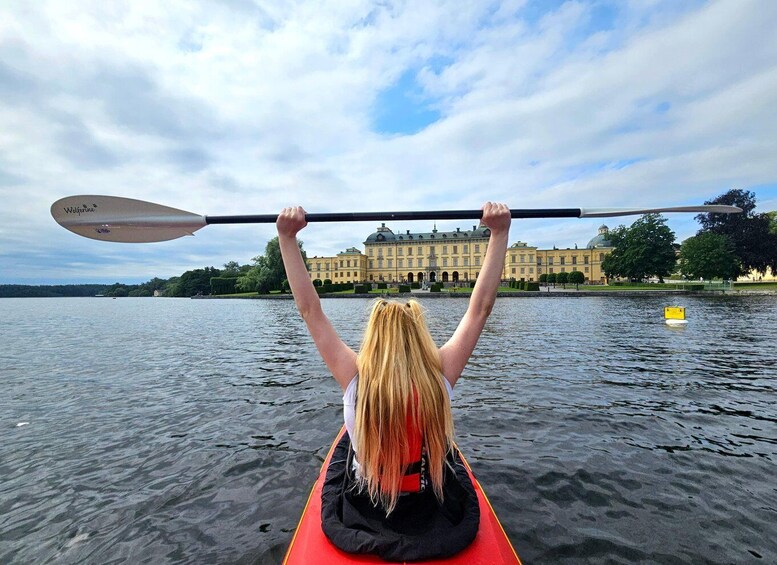 A person kayaking on a calm lake with a historic building in the background. 2