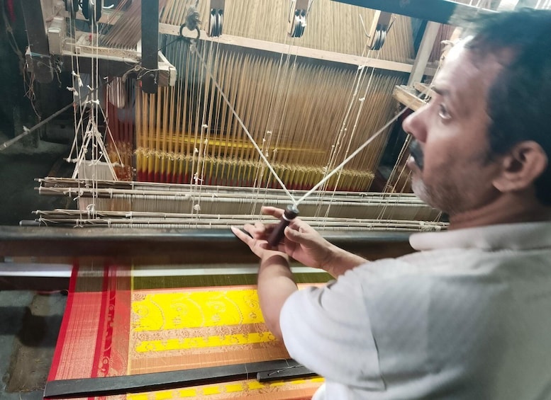 A person weaving on a loom with a colorful fabric partially completed. 4