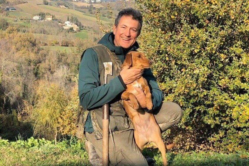 A person holding a dog in a natural landscape with hills and vegetation. 1