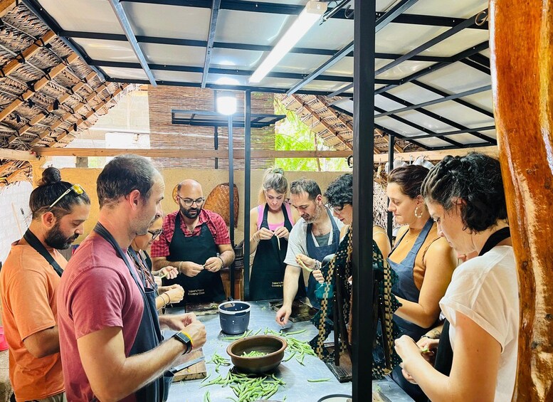 A group of people engaged in cooking activities in an outdoor kitchen setting. 5