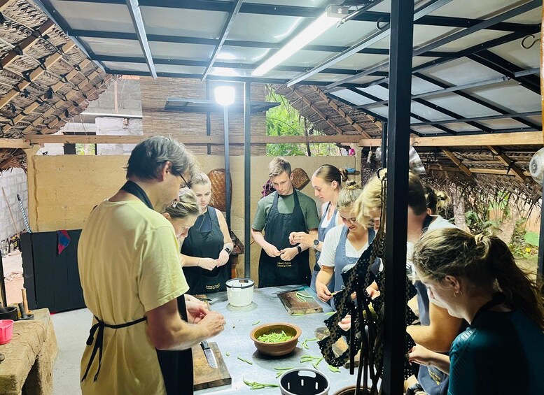 A group of people engaged in a cooking activity in a rustic kitchen setting. 4