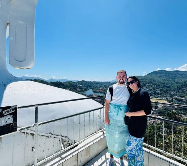 A man and a woman standing on a balcony with a scenic view of a lake and mountains. 4