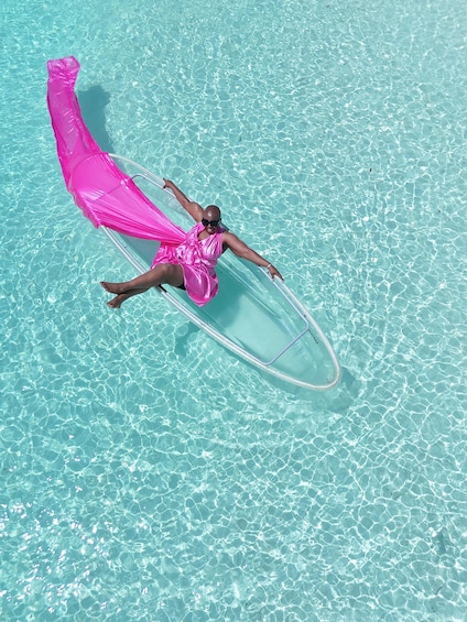 En person flyder i en klar, blå pool med et pink stof. 3