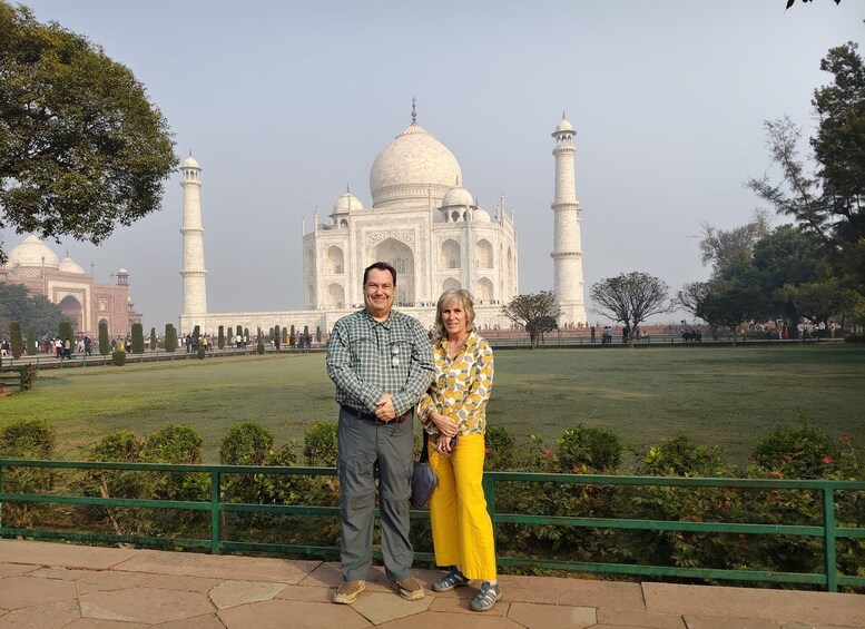 A couple standing in front of the Taj Mahal with the mausoleum and minarets in the background. 2