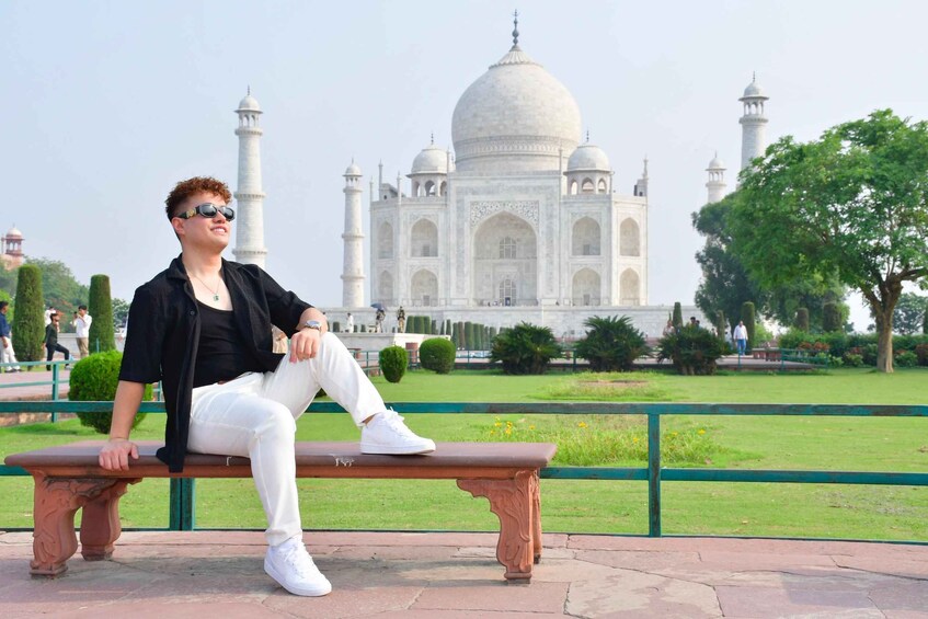 A person sitting on a bench with the Taj Mahal in the background. 1
