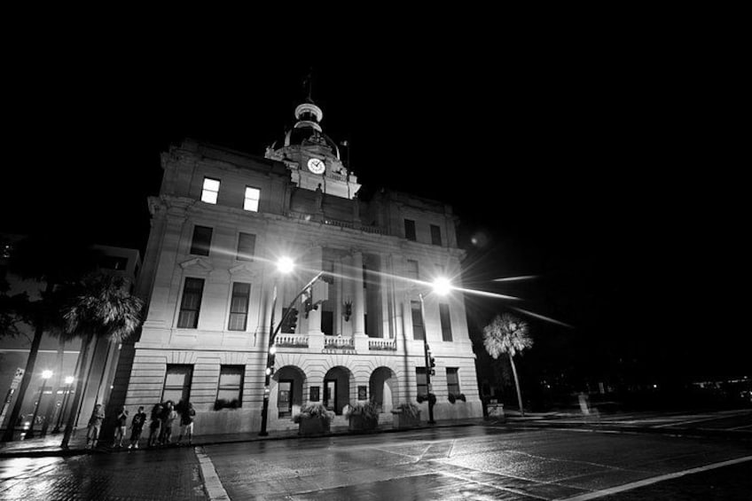 A large, illuminated building with a clock tower at night. 2