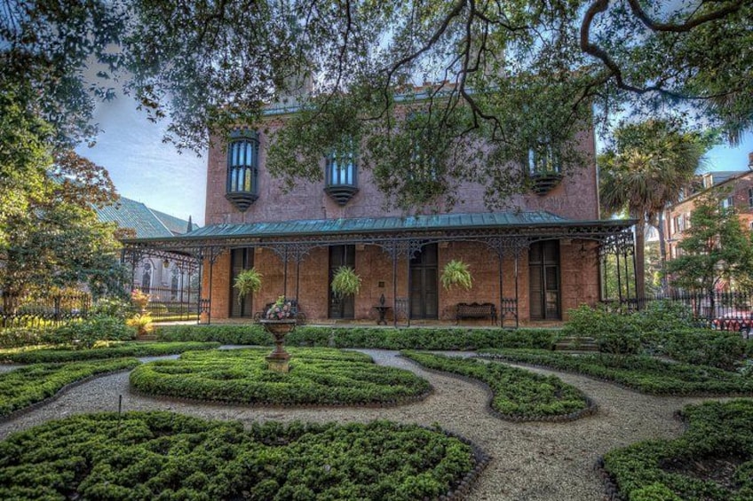 A brick building with a green roof, surrounded by a well-manicured garden with a central fountain. 1