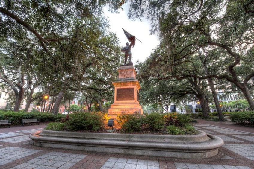 A statue in a park with trees and a paved walkway. 5