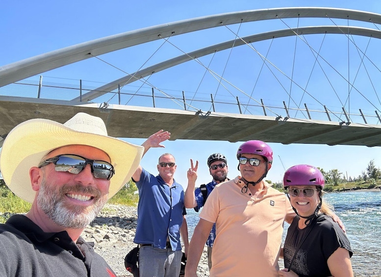 A group of people standing under a bridge with a river in the background. 5