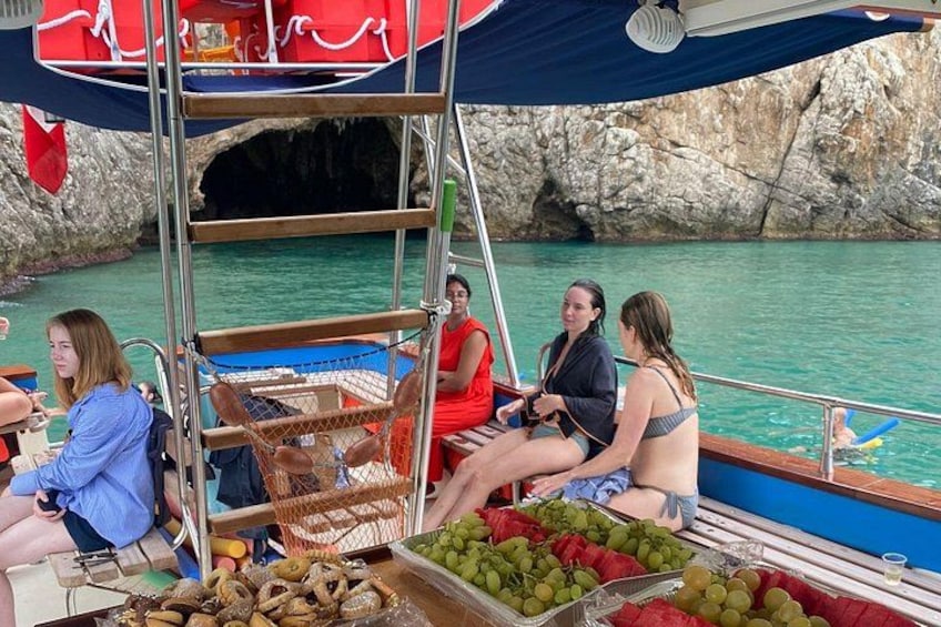 A group of people on a boat with a rocky coastline in the background. 3