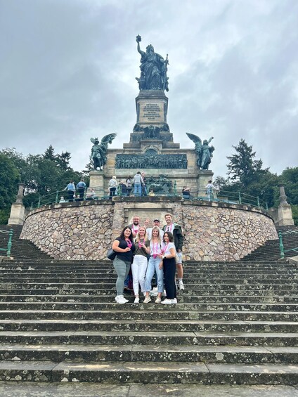 A group of people standing on stone steps in front of a monument with statues and inscriptions. 2