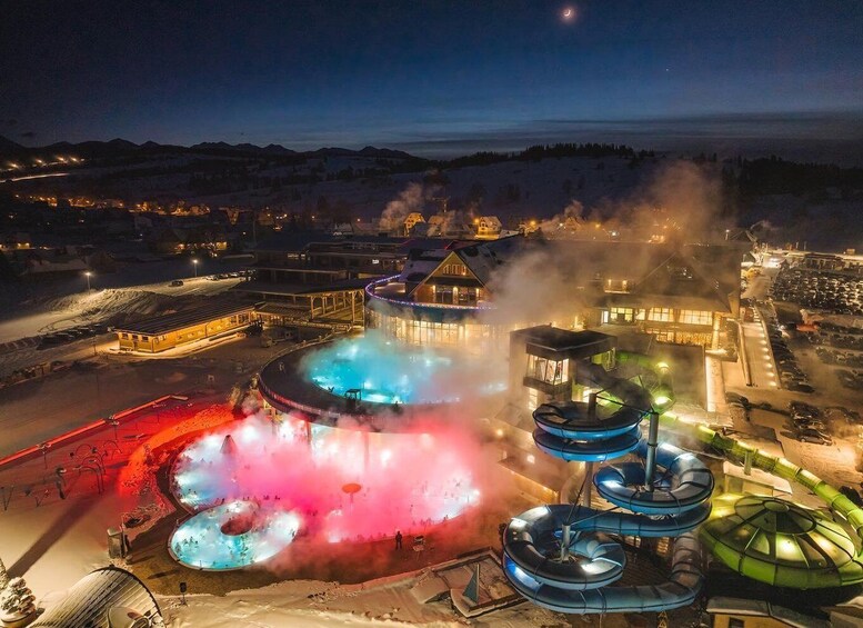 A hot spring resort at night with illuminated pools and steam rising. 5