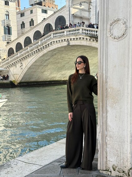 Une femme se tient près d’un canal, avec un pont de pierre en arrière-plan. 2