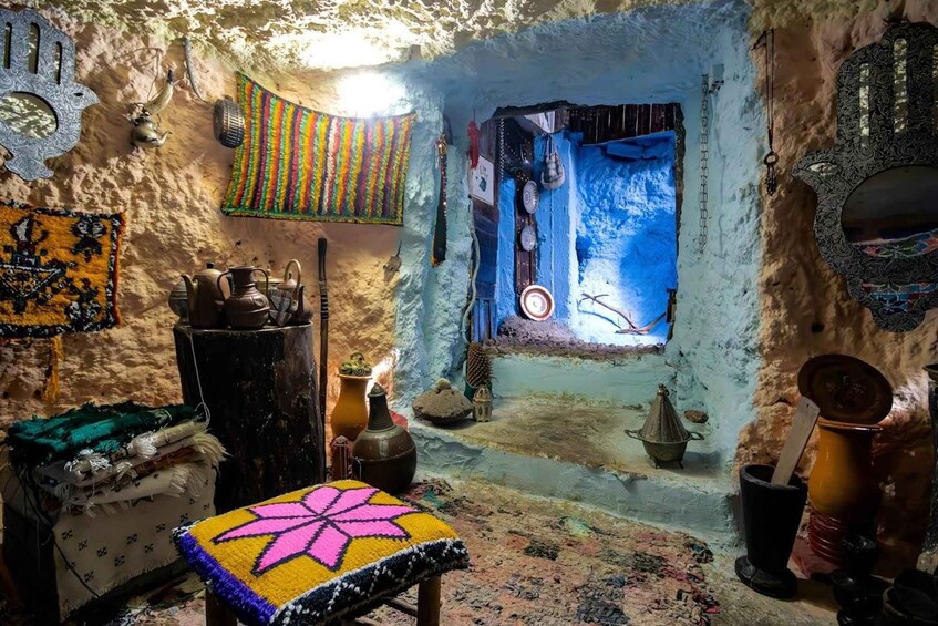 A traditional room with a blue wall, a colorful rug, and various pottery. 3