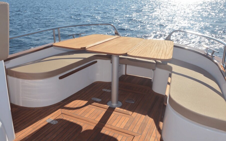 A boat's deck with a wooden table and cushioned seating. 5