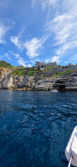 A coastal landscape with a historic castle on a hill, rocky cliffs, and calm sea. 3