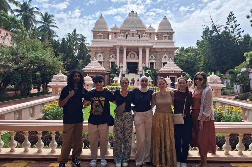 A group of people posing in front of a large, ornate building with domes and a garden. 3