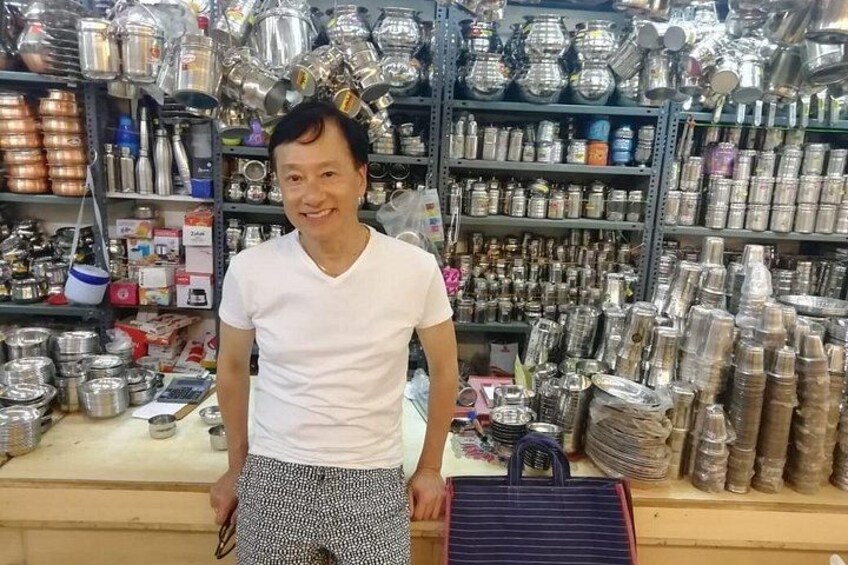 Eine Person steht in einem Laden, dessen Regale mit Metallbehältern und Gläsern gefüllt sind. 4