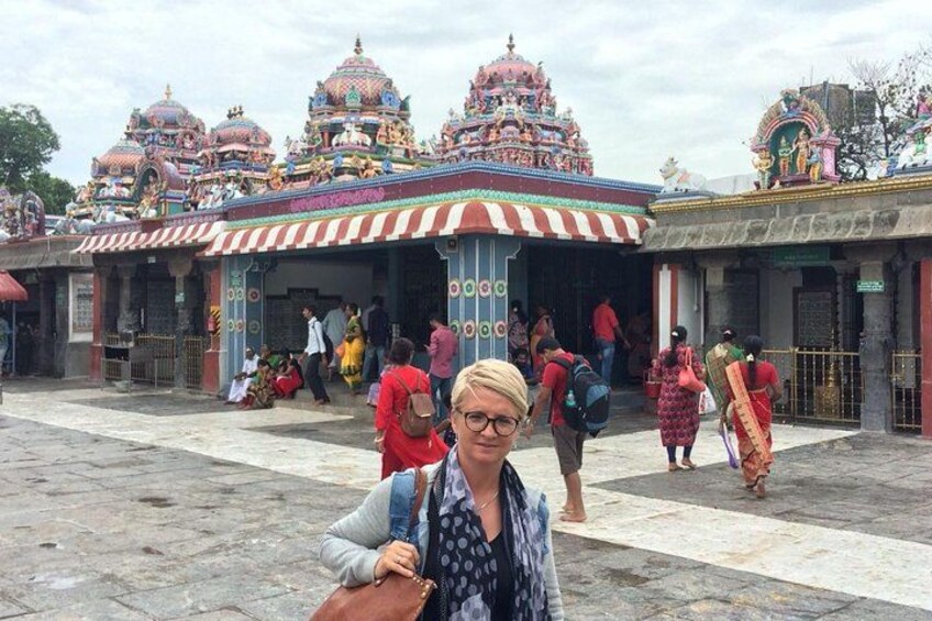 A temple with colorful domes and a striped roof. People are walking around and some are sitting on the ground. 2