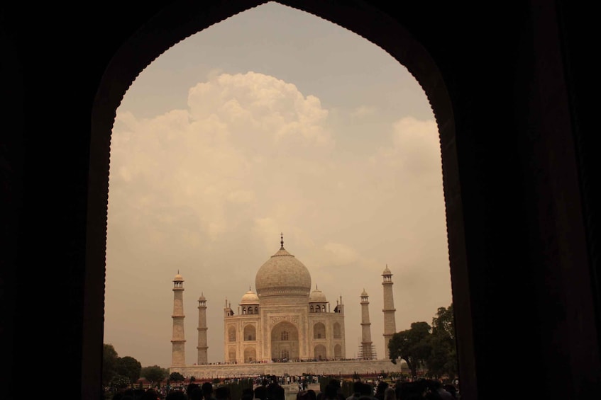 The Taj Mahal framed by an archway, with a crowd in the foreground. 5