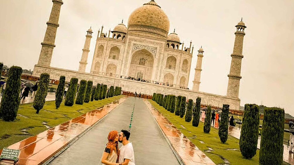 The Taj Mahal with a couple kissing in the foreground. 3