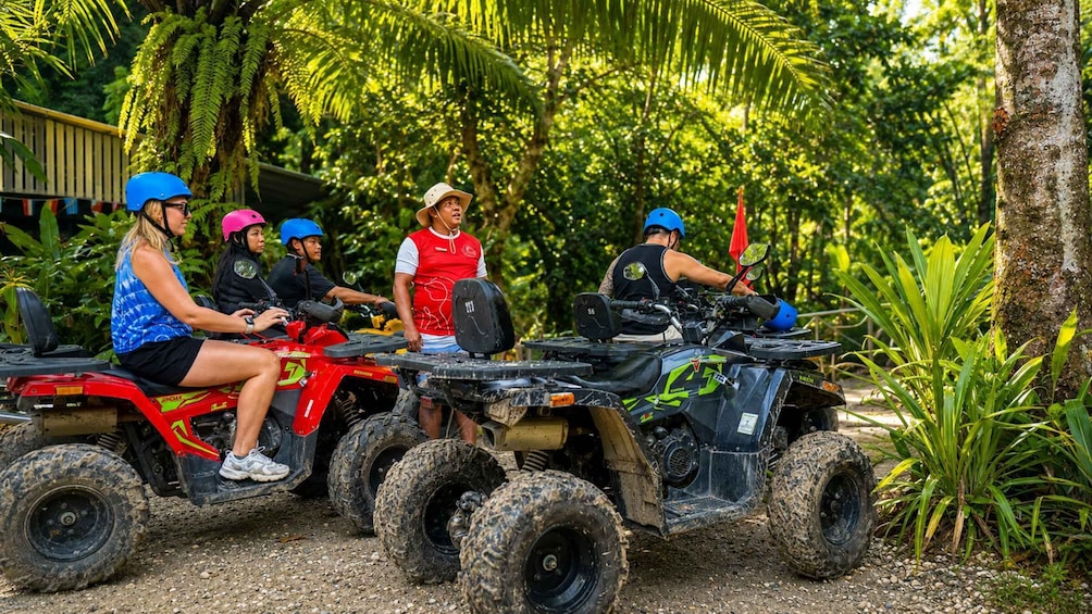 A group of people on ATVs in a tropical setting with dense foliage. 2