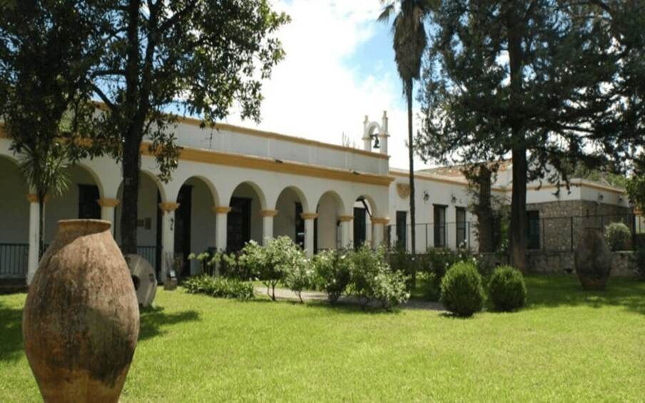A building with arched windows and a white facade, surrounded by a well-maintained lawn and trees. 4