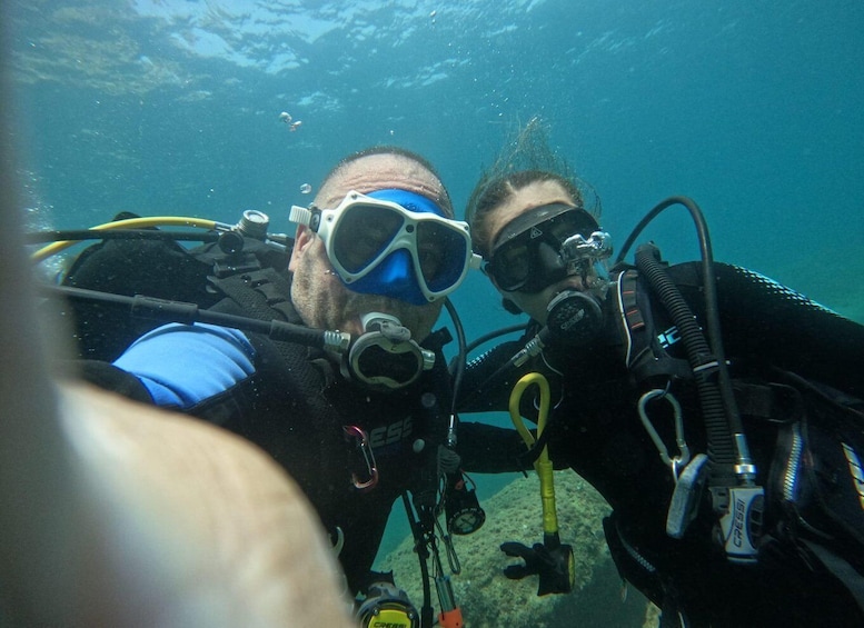 Zwei Taucher unter Wasser mit Ausrüstung, Blasen und einem sandigen Meeresgrund. 2