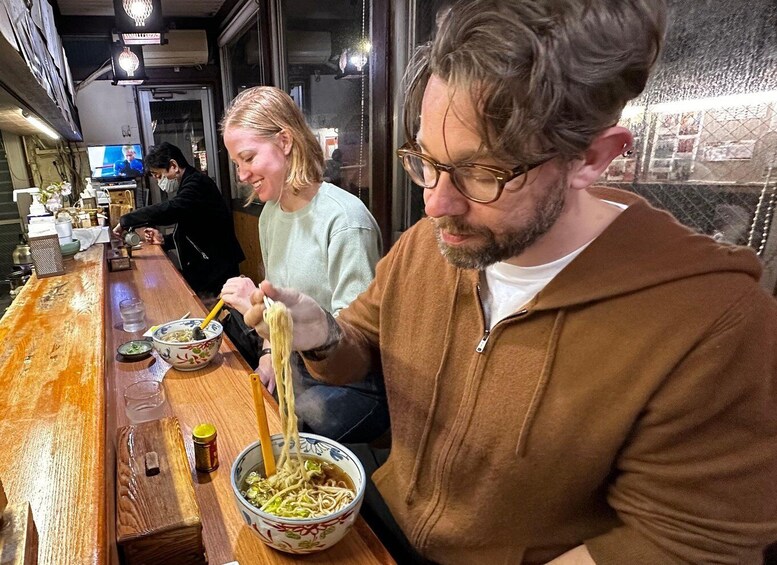 Una persona menjant noodles a taula de fusta en un restaurant. 1