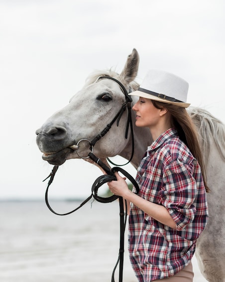 A person holding a horse's reins on a beach. 1