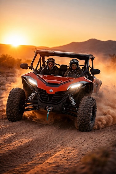 A red ATV with two people driving on a dirt road during sunset. 1
