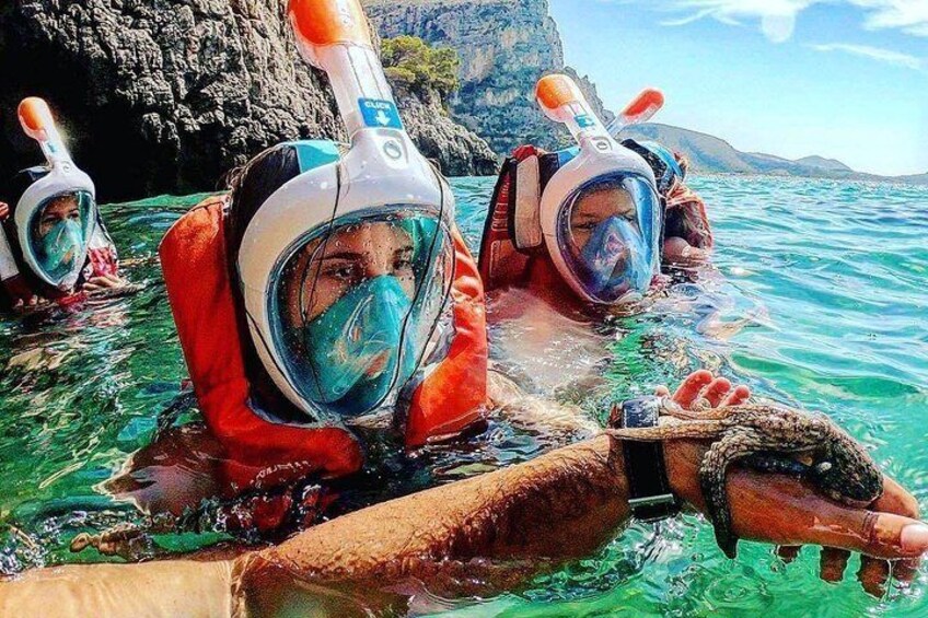 Deux personnes font de la plongée avec tuba dans une eau claire, avec des falaises rocheuses en arrière-plan. 5